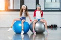 Two little girls in sportswear sitting at fitness studio Royalty Free Stock Photo
