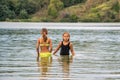Two little girls stand waist-deep in the river