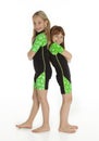 Two Little Girls Standing Back to Back Wearing Wetsuits