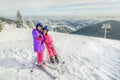 Two little girls standing with skiis on the top of snowy mountain and taking a selfie