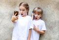 Two little girls with their mobile phones, excited children taking selfies with a smartphone and talking on the phone Royalty Free Stock Photo