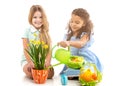 Two little girls watering flowers and playing on the floor Royalty Free Stock Photo