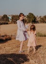 Two little girls wearing boho style dresses walking together in summer field with dry grass. Kids having fun in summer day Royalty Free Stock Photo