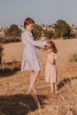 Two little girls wearing casual dresses walking together in summer field with dry grass. Kids having fun in summer day Royalty Free Stock Photo