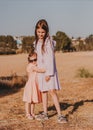 Two little girls wearing eco style dresses walking together in summer field and hugging. Kids having fun in summer day Royalty Free Stock Photo