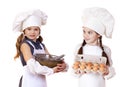 Two little girls in a white apron holding box of raw eggs and bo