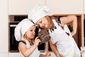 Two little girls in white chef hats play fun in the kitchen. Children cook food