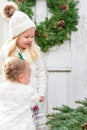 Two little girls in white jackets standing in front of a rustic white door in winter Royalty Free Stock Photo