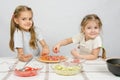 Two little happy girl at spread on the pizza ingredients Royalty Free Stock Photo