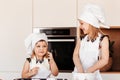 Two little happy girls in chef hats play with flour in the kitchen Royalty Free Stock Photo