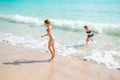 Two little happy girls have a lot of fun at tropical beach playing together at shallow water. Kids splashing. Royalty Free Stock Photo