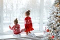 Two little happy girls are watching the first snow through the window Royalty Free Stock Photo