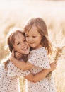 Two little happy identical twin girls playing together in nature in summer. Girls friendship and youth concept. Active children`s