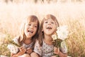 Two little happy identical twin girls playing together in nature in summer. Girls friendship and youth concept. Active children`s