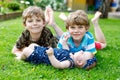 Two little happy kid boys with newborn baby girl, cute sister. Siblings on grass in summer or spring in garden. Kids