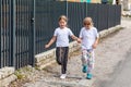 Two little happy school age girls, cheerful children jumping, running down the street alone holding hands and smiling, road side Royalty Free Stock Photo