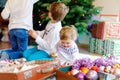 Two little kid boys and adorable baby girl decorating Christmas tree with old vintage toys and balls. Family Royalty Free Stock Photo