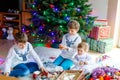 Two little kid boys and adorable baby girl decorating Christmas tree with old vintage toys and balls. Family Royalty Free Stock Photo