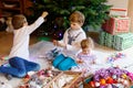 Two little kid boys and adorable baby girl decorating Christmas tree with old vintage toys and balls. Family Royalty Free Stock Photo