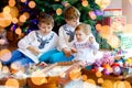 Two little kid boys and adorable baby girl decorating Christmas tree with old vintage toys and balls. Family Royalty Free Stock Photo