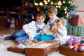 Two little kid boys and adorable baby girl decorating Christmas tree with old vintage toys and balls. Family Royalty Free Stock Photo