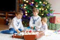 Two little kid boys and adorable baby girl decorating Christmas tree with old vintage toys and balls. Family Royalty Free Stock Photo