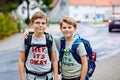 Two little kid boys with backpack or satchel. Schoolkids on the way to school. Healthy adorable children, brothers and