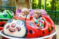 Two little kid boys on carousel in amusement park