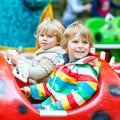 Two little kid boys on carousel in amusement park