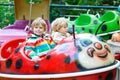 Two little kid boys on carousel in amusement park