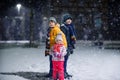 Two little kid boys and cute toddler girl sitting together playing with snow on winter night. Siblings, brothers and Royalty Free Stock Photo
