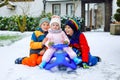 Two little kid boys and cute toddler girl sitting together on sledge. Siblings, brothers and baby sister enjoying sleigh Royalty Free Stock Photo