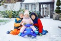 Two little kid boys and cute toddler girl sitting together on sledge. Siblings, brothers and baby sister enjoying sleigh Royalty Free Stock Photo