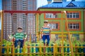 Two little kid boys having fun with swing on outdoor playground. Children, best friends and siblings swinging on warm sunny spring Royalty Free Stock Photo