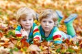 Two little kid boys laying in autumn leaves in colorful clothing Royalty Free Stock Photo