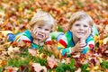 Two little kid boys laying in autumn leaves in colorful clothing Royalty Free Stock Photo