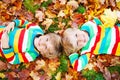 Two little kid boys laying in autumn leaves in colorful clothing Royalty Free Stock Photo