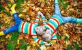 Two little kid boys laying in autumn leaves in colorful clothing Royalty Free Stock Photo