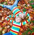 Two little kid boys laying in autumn leaves in colorful clothing Royalty Free Stock Photo