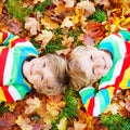 Two little kid boys laying in autumn leaves in colorful clothing Royalty Free Stock Photo