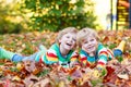 Two little kid boys laying in autumn leaves in colorful clothing Royalty Free Stock Photo