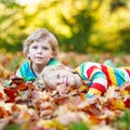 Two little kid boys laying in autumn leaves in colorful clothing Royalty Free Stock Photo