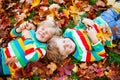 Two little kid boys laying in autumn leaves in colorful clothing Royalty Free Stock Photo