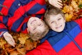 Two little kid boys lying in autumn leaves in colorful fashion fall clothing.