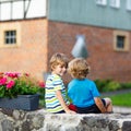 Two little kid boys sitting together on stone bridge Royalty Free Stock Photo