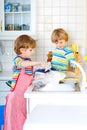 Two little kid boys washing dishes in domestic kitchen