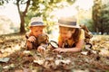 Two little kids with backpacks examining plants through magnifying glass in forest Royalty Free Stock Photo