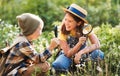 Two little kids with backpacks examining plants through magnifying glass in forest Royalty Free Stock Photo