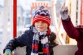 Two little kids, boy and girl having fun on ferris wheel on traditional German Christmas market during strong snowfall