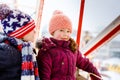 Two little kids, boy and girl having fun on ferris wheel on traditional German Christmas market during strong snowfall